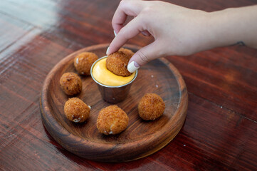 beautiful woman holding crispy fast food dipping in cheese sauce
