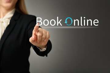 Young woman using virtual screen for online booking on grey background