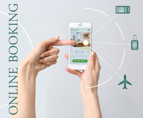 Young woman with mobile phone booking room in hotel online against grey background