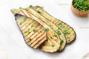 Tasty grilled eggplant and parsley on table