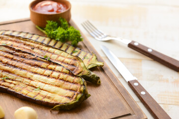 Tasty grilled eggplant with ketchup and garlic on table