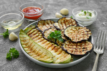 Tasty grilled eggplant with sauces in plate on gray background