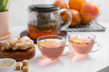 Cups of healthy tea with lemon and ginger on table