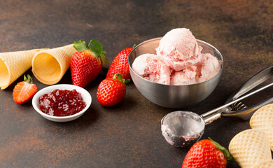 Homemade strawberry ice cream in waffle cones on dark vintage background. Healthy summer food concept.