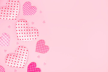 Valentine's or Mother's Day background. Fabric hearts with different patterns on pastel pink with copy space. Cozy hearts backdrop. Heart shaped cushions.