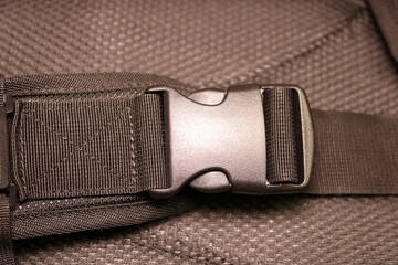 Black plastic buckle on the backpack. Plastic zip lock. Photo toned sepia. Close-up.