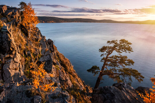 Beautiful lake and rocky shore in the rays of evening sun of golden autumn © Dushlik