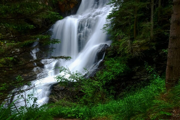 gorgeous large waterfall in a green forest while hiking