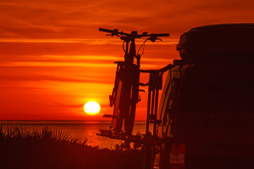 Camper with bicycles on rack camping on beach at sunrise