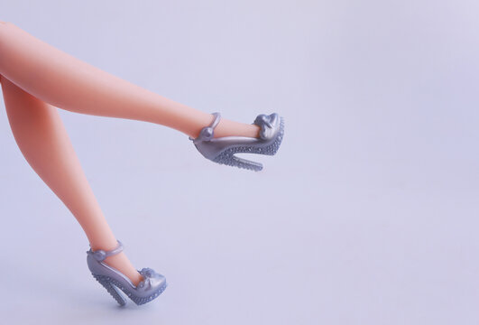 Long skinny legs of a plastic toy doll and high heels shoes. Doll shoes set. Fashion concept.