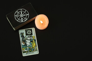 Tarot cards are placed next to a deck of cards with white candles lit. With a black space on the left to write a message.