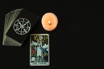 The Tower Tarot cards With a white candle lit With a black space on the left to write a message.