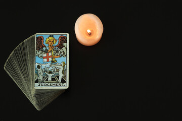 The Judgement Tarot cards With a white candle lit With a black space on the left to write a message.