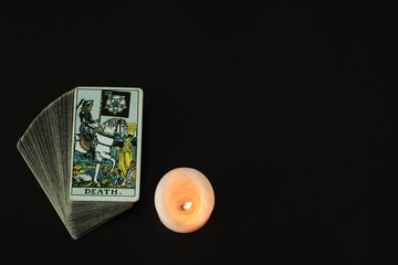 Death Tarot cards With a white candle lit With a black space on the left to write a message.