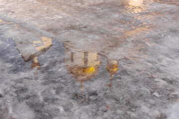 Reflection of the dome of the temple in the frozen melted snow