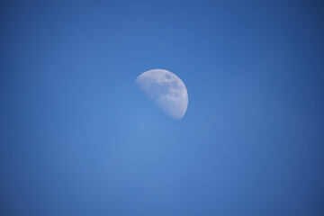 The moon in the blue sky at day time.