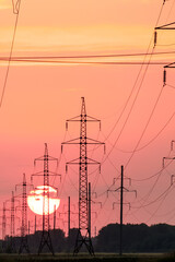 sun in wires on power lines, landscape at sunset of a summer day of current-carrying lines to the...