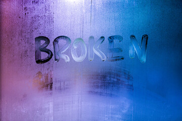 the word broken handwritten on wet window glass