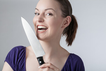 A young woman is playing with a sharp kitchen knife 