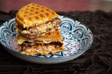 Fresh waffles with peanut butter and chocolate spread on a decorated plate.