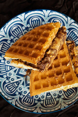 Fresh waffles with peanut butter and chocolate spread on a decorated plate.