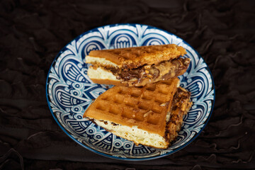 Fresh waffles with peanut butter and chocolate spread on a decorated plate.