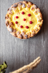 Top view on fresh and crispy baked at home cheese pie on gray wooden background. Baking pastries on holidays. Close up on golden color cheesecake.  Desserts flat lay for bakery or restaurants