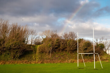 Training pitch with Irish National goal post for hurling, rugby, camogie and football, Rainbow in the blue cloudy sky. Nobody