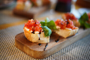 Bruschetta with tomatoes, mozzarella and basil on a cutting board.