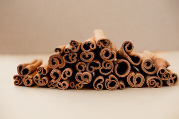 many sticks of high-quality cinnamon lie in a pile on a beige background. savoury spices for cooking. Monochrome food photography, selective focus