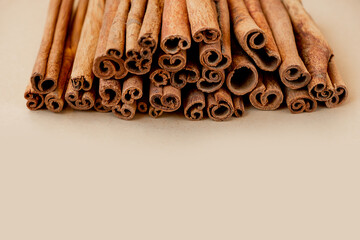 many sticks of high-quality cinnamon lie in a pile on a beige background. savoury spices for cooking. Monochrome food photography, selective focus, space for text