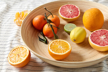 food, healthy eating and vegetarian concept - close up of citrus fruits on wooden plate