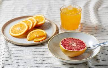 food, healthy eating and fruits concept - still life of grapefruit, sliced orange and glass of juice over drapery