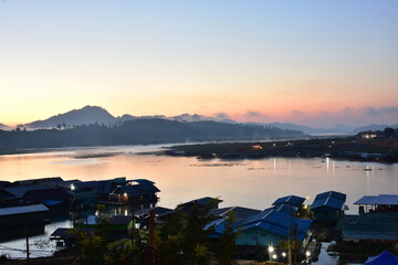 An early morning view with beautiful colorful lights Before sunrise At the Fisherman Village near Mon Market at Mon Bridge, Sangkhlaburi District, Kanchanaburi Province, Thailand