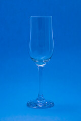 Empty wine or champagne glass on a blue background. The glitter of glasses.
