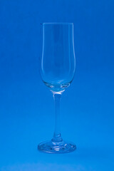Empty wine or champagne glass on a blue background. The glitter of glasses.