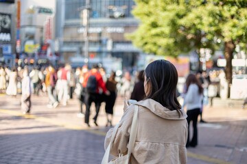 渋谷駅前でスマートフォンを見る若い女性