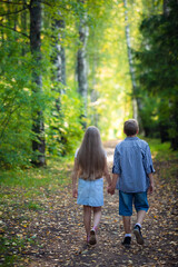 Fototapeta premium Beautiful boy and girl walking in the beautiful summer forest