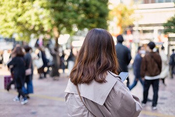 渋谷駅前でスマートフォンを見る若い女性