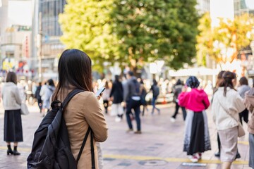 Fototapeta premium 渋谷駅前でスマートフォンを見る若い女性