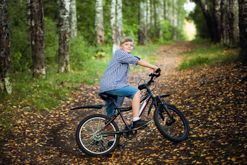 Naklejka premium Preteen handsome boy with bicycle on the forest path