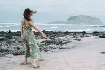 A young woman seen from the behind with a vaporous floral dress on a windy day on the island of La...
