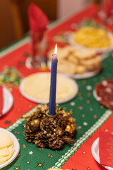 candle lit on an elegant home table decorated with Christmas motifs and lots of food 