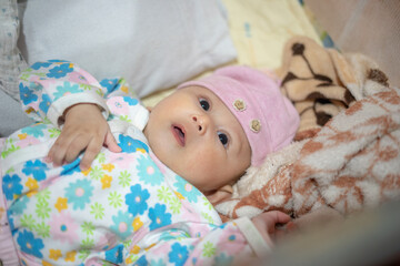 Three month old baby girl laying in a warm bed during the winter cold