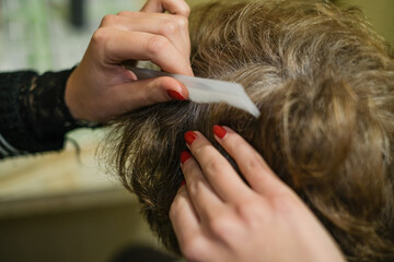Fototapeta premium Hair dresser girl while applying hair dye to a white haired elderly woman customer at work,home beauty treatment