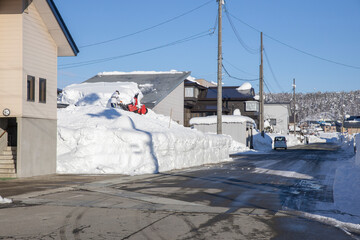 住宅の屋根から落ちた雪の除雪風景