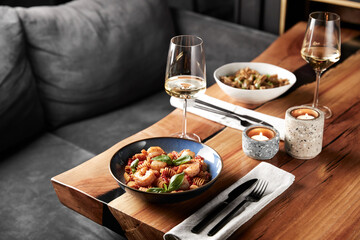 Romantic candlelit dinner for two in a cozy atmosphere with pasta with seafood and white wine in glasses