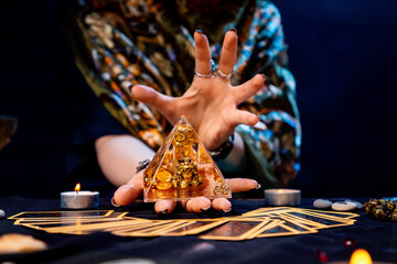 The fortune teller holds a glass pyramid with gold in her hands and casts a spell over it. There...