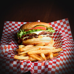 Cheese burguer sandwich with fries on paper with black background