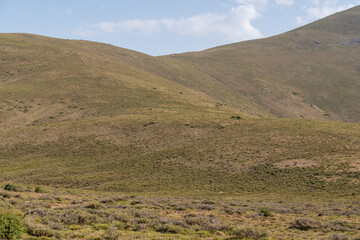 Obraz premium mountainous landscape of Sierra Nevada in southern Spain, there are bushes and grass, there are stones and the sky has clouds